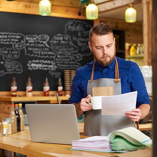 Small business owner with apron reviewing business documents